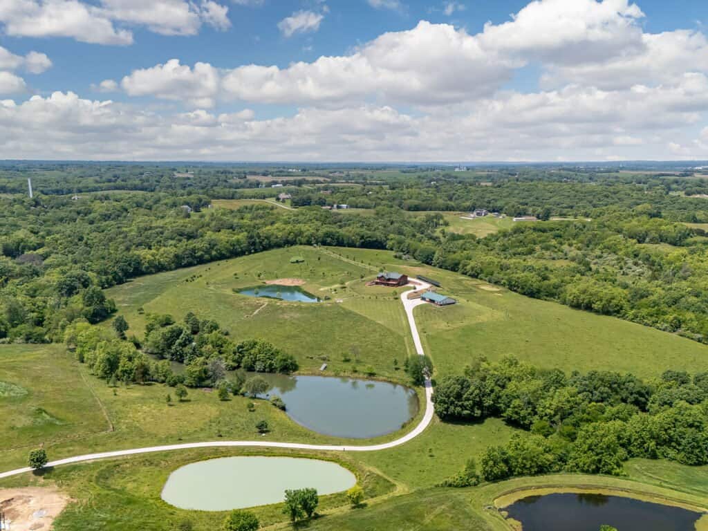 Aerial view of Selah Hills Ranch, two ponds and thirty acres of pasture and woods with the lodge and guest building along the gravel drive near Agency, Missouri.