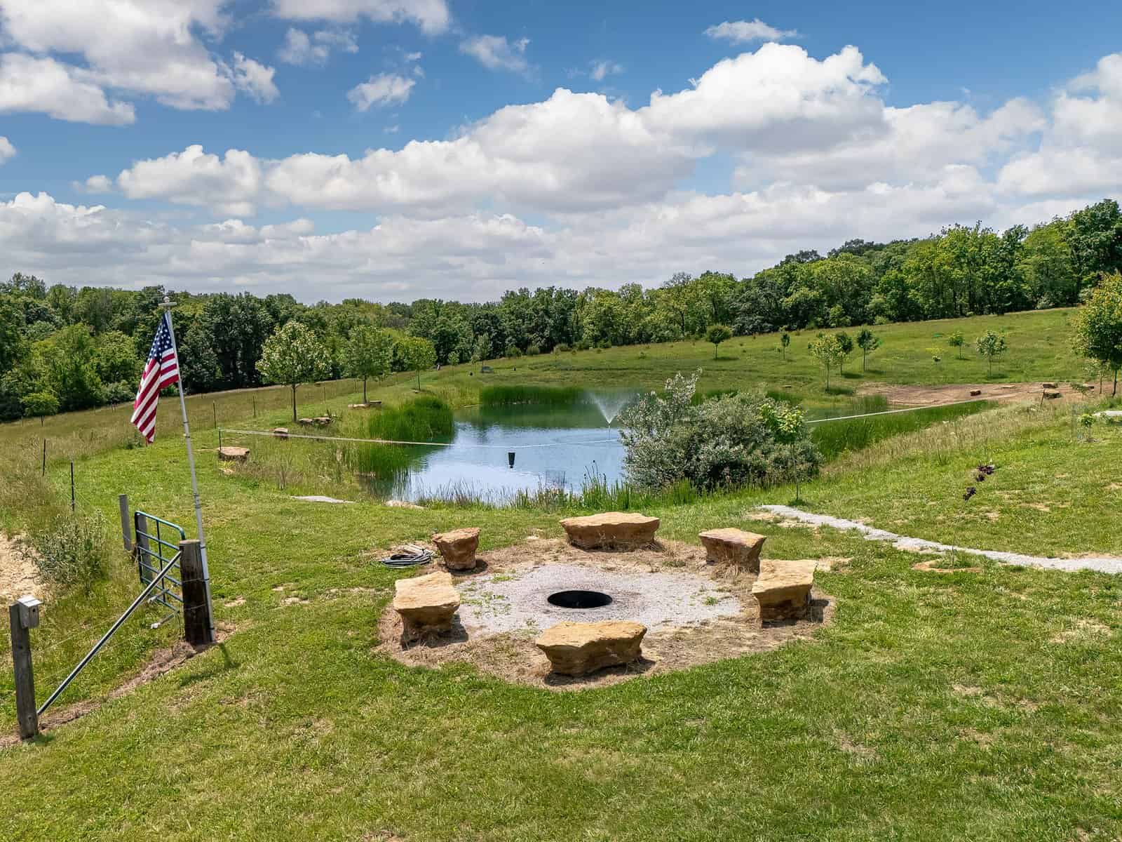 The bonfire pit at Selah Hills Ranch, ringed with rustic limestone boulders for seating, overlooking the stocked pond and pasture.