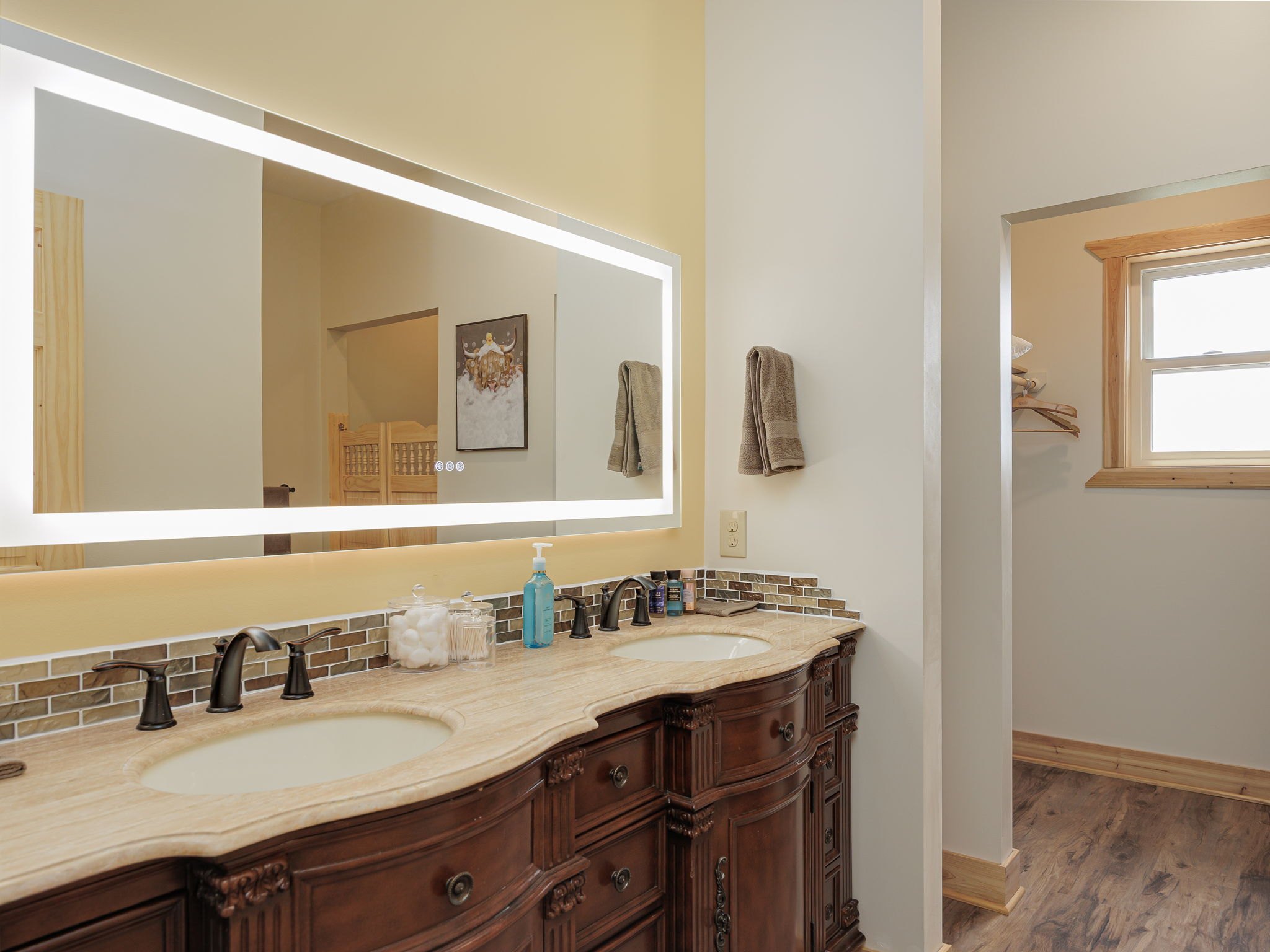 A guest bathroom at Selah Hills Ranch with a double vanity beneath a backlit mirror.