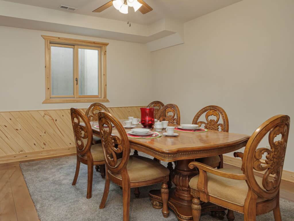 The dining room at Selah Hills Ranch, a carved wooden table set for six under a ceiling fan.