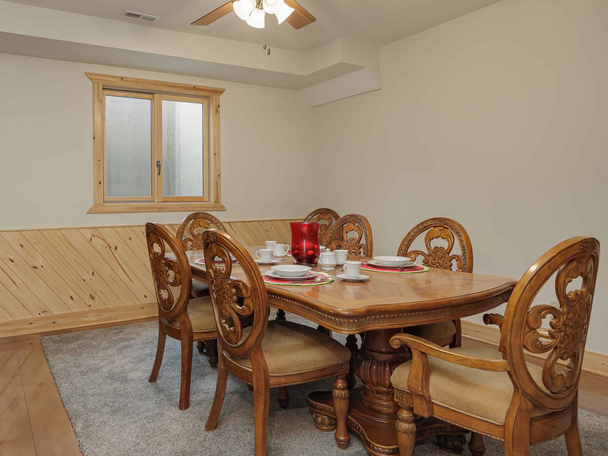 The dining room at Selah Hills Ranch, a carved wooden table set for six under a ceiling fan.