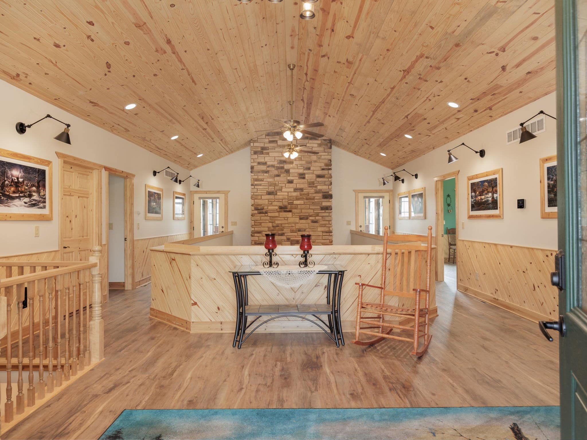 The guest entry hall at Selah Hills Ranch, an arched knotty pine ceiling above a stone chimney, a console table and rocking chairs.