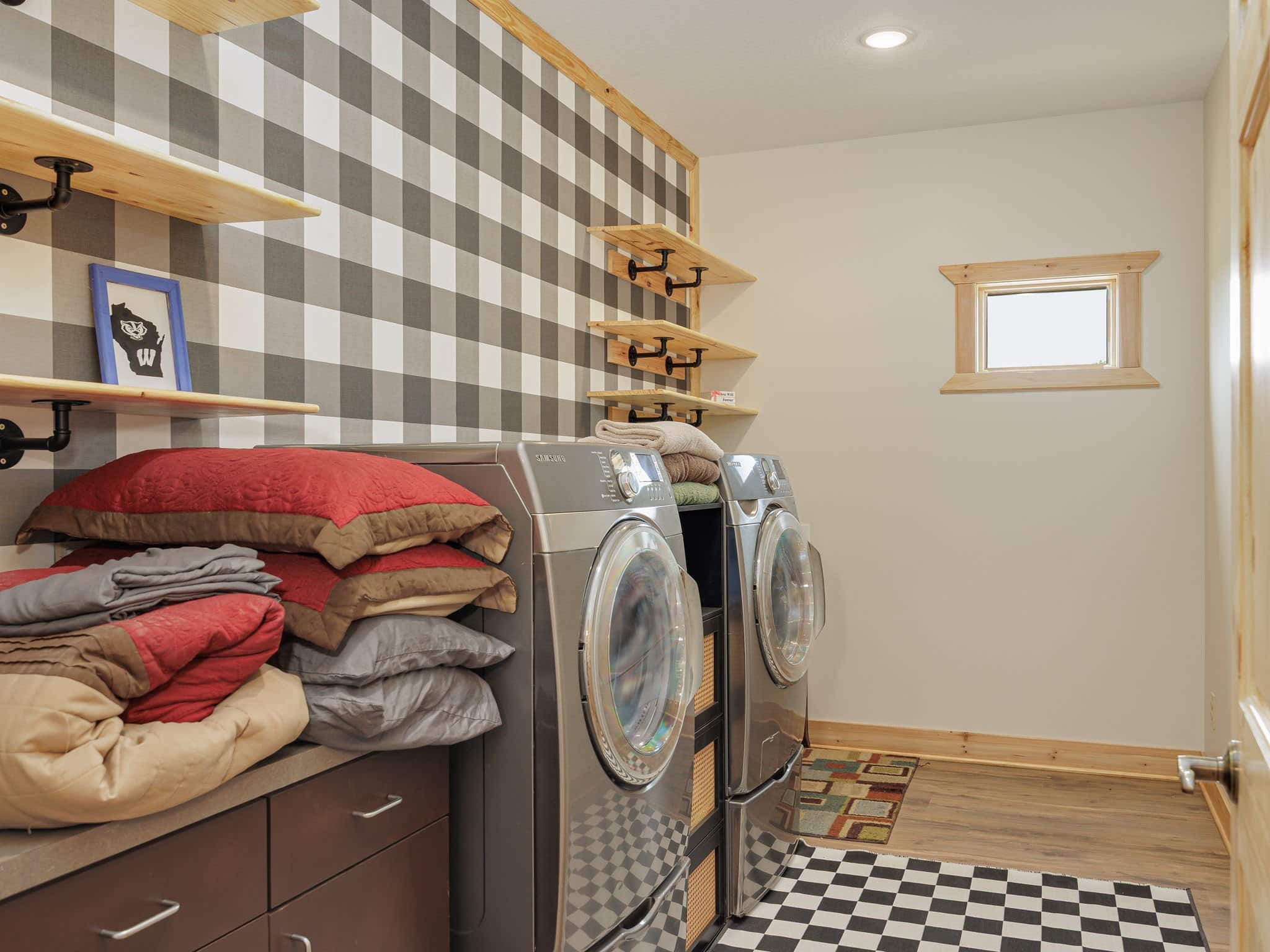 The guest laundry at Selah Hills Ranch, a full-size washer and dryer on a checkered floor with folded blankets stacked on the counter.